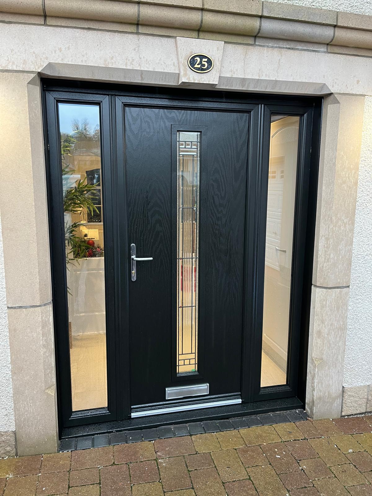 Black anthracite composite front door with full-height sidelights and a stone surround