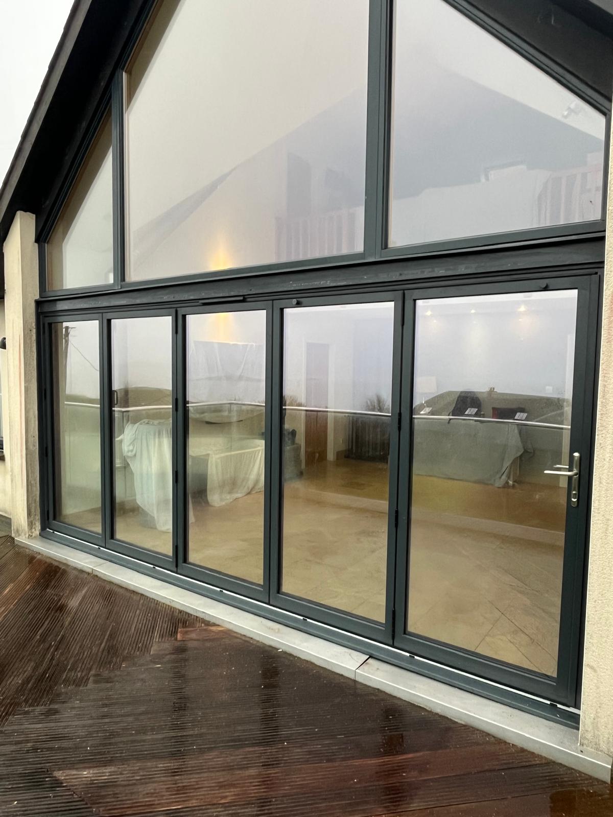 Wide anthracite aluminium bifold doors and apex window from a decked patio