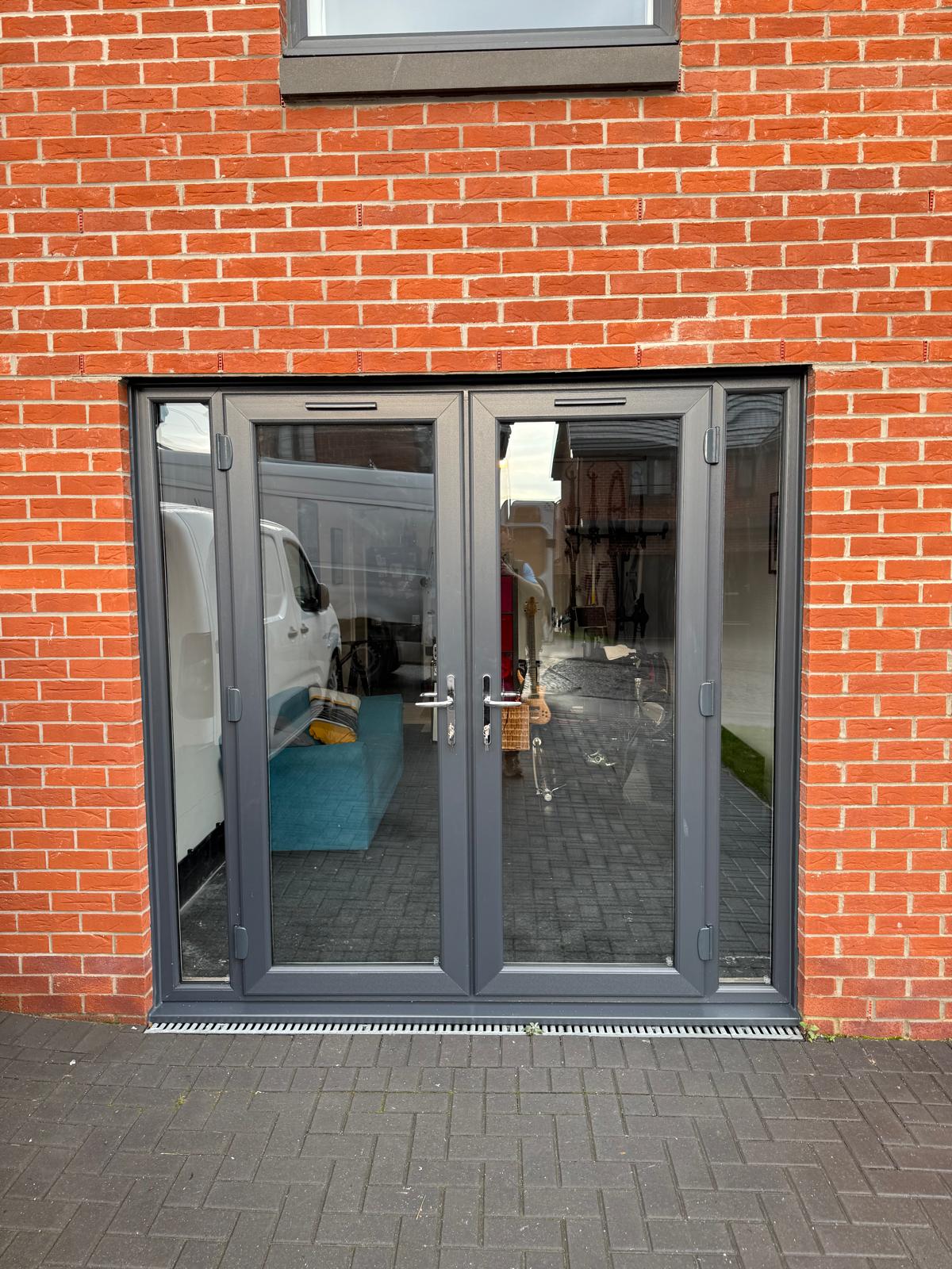 Anthracite French doors with a top transom on a black brick surround