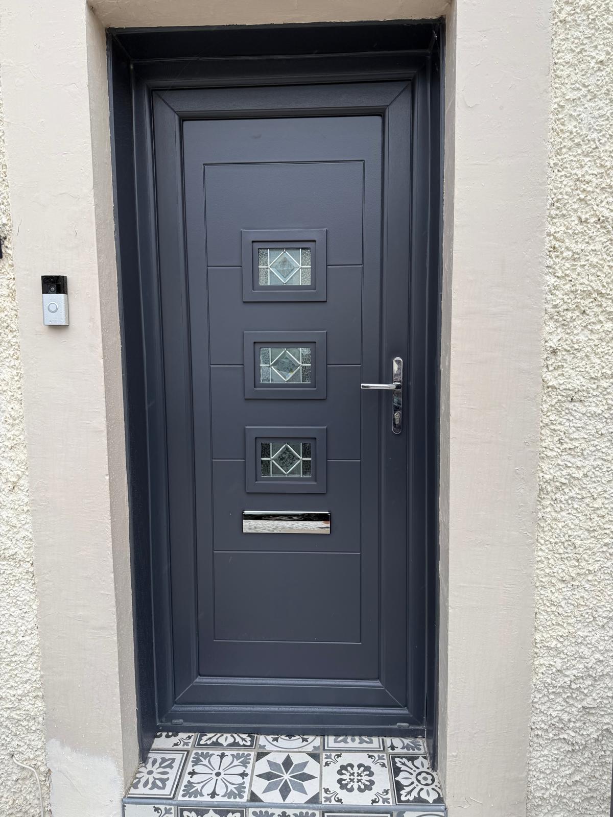 Anthracite door with three leaded glass squares on a patterned tile step
