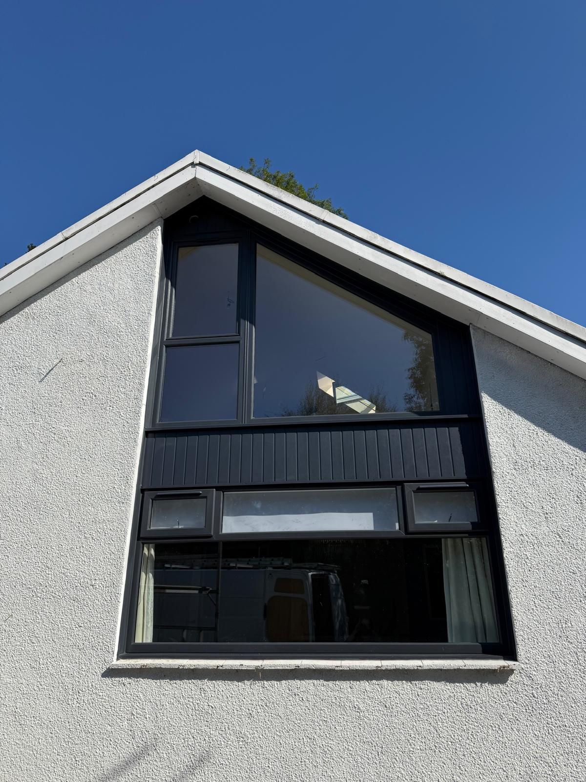 Triangular apex window in black aluminium frame against a deep blue sky