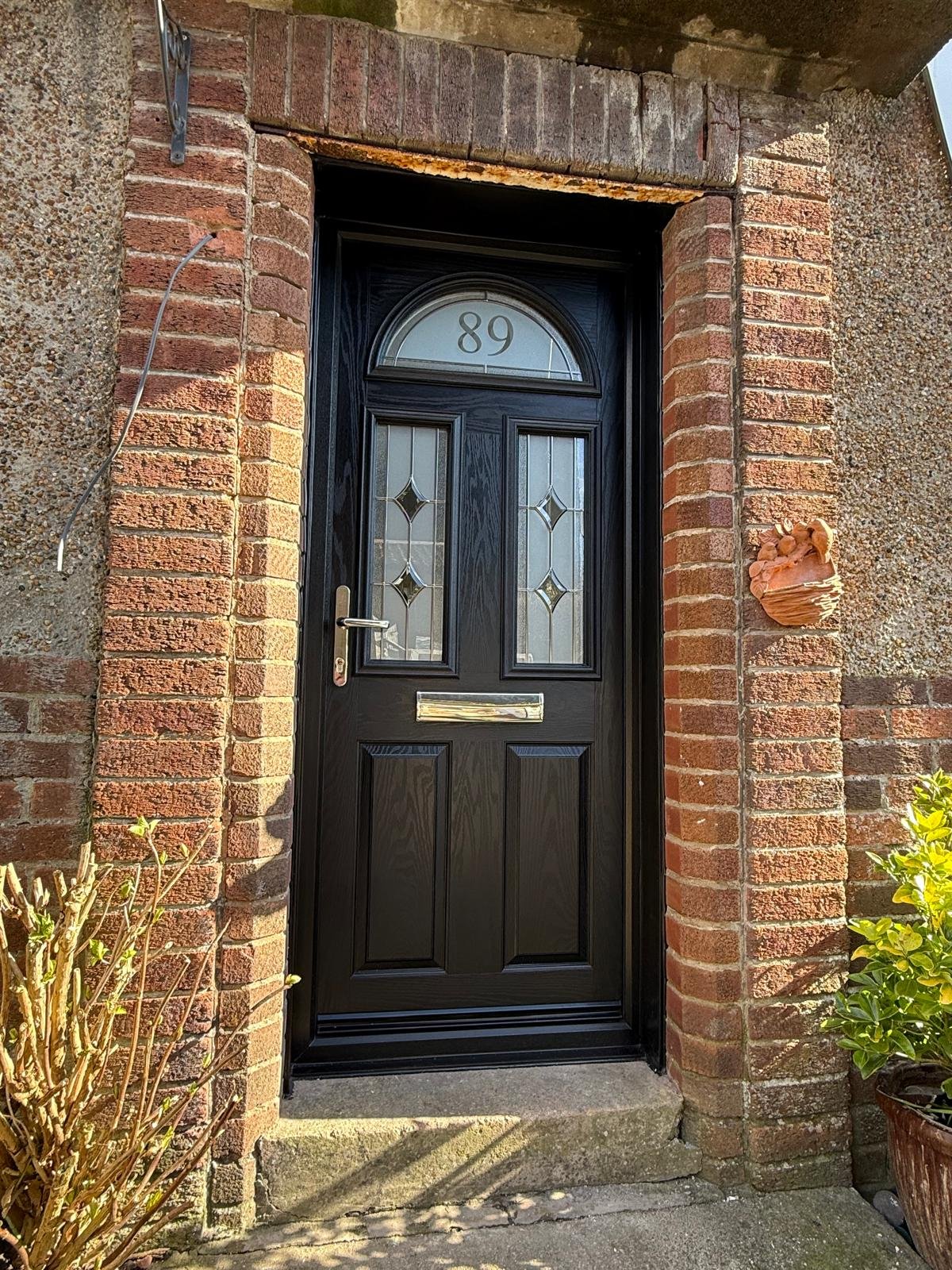 Black composite door with leaded diamond glass and a traditional brick surround
