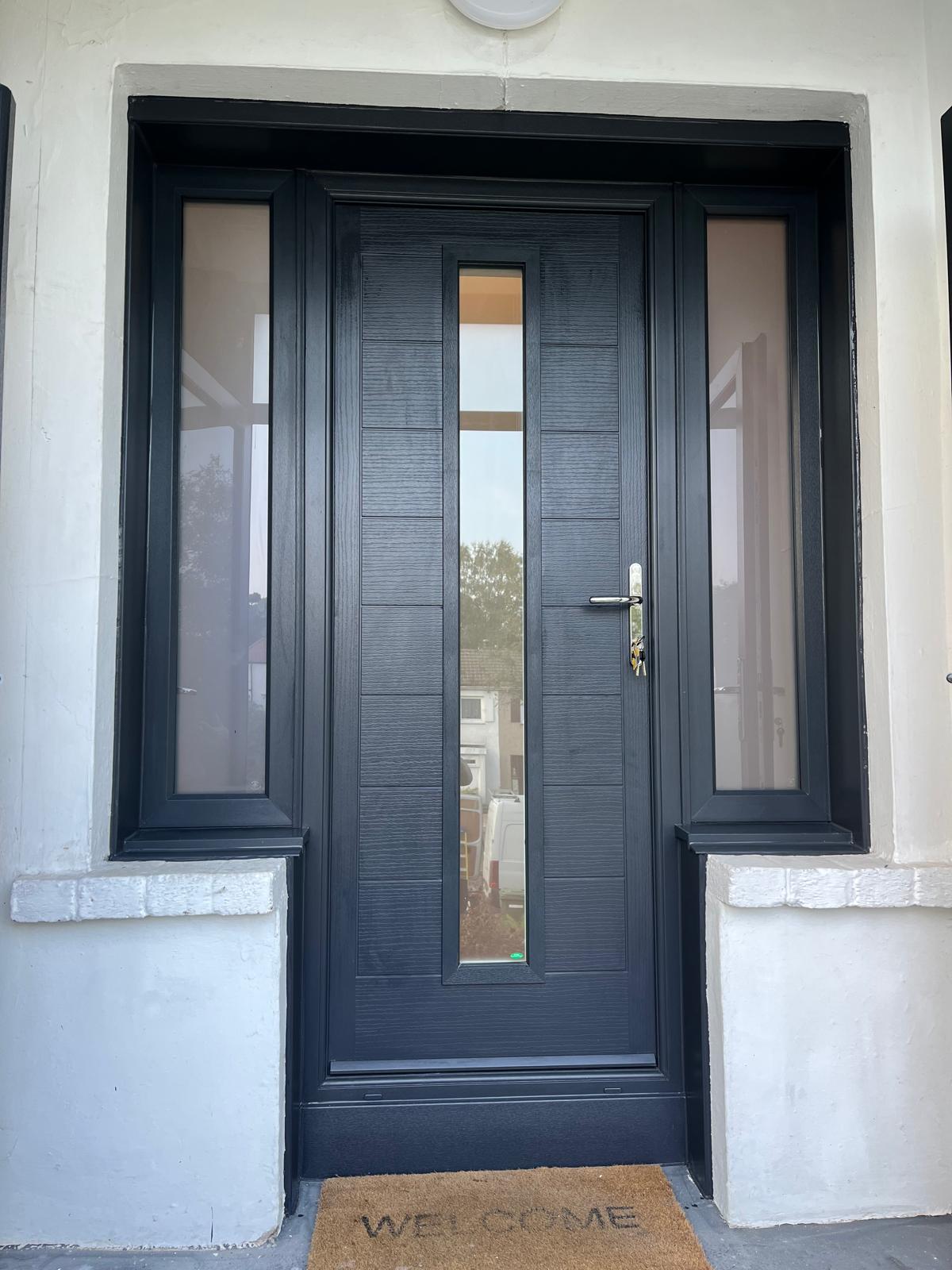 Black composite door with twin sidelights and a vertical centre glass strip on a white render porch