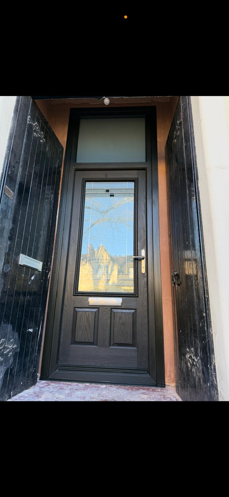 Black panelled door with a top fan light in a traditional Glasgow tenement entry