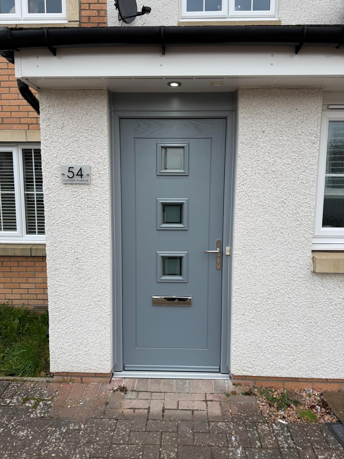 Grey composite front door with porthole panels and house number 54