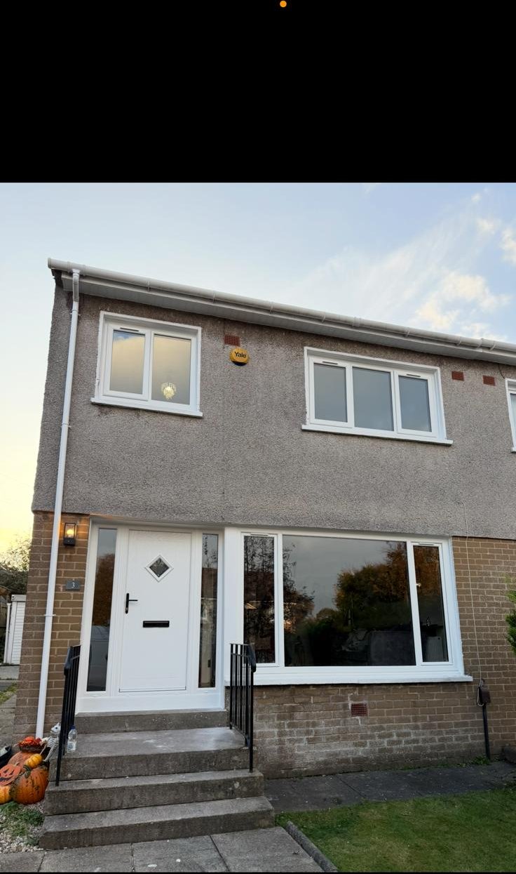 Full house exterior with new white windows and a composite front door at dusk
